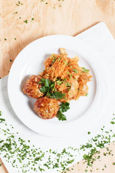 köfte ve ahşap arka plan üzerinde beyaz bir tahta üzerinde beyaz bir tabakta yeşillik ile haşlanmış lahana