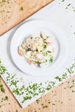 Yengeç sopa, Mısır ve ahşap arka plan üzerinde yeşillikleri ile beyaz kesme tahtası üzerinde beyaz bir tabakta sonbahar sebze salatası