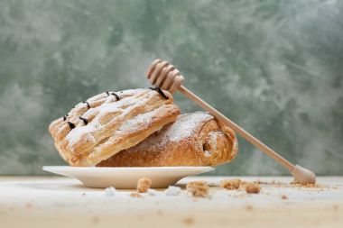 bir puf kek meyve doldurma ve çikolata beyaz tabakta ile pudra şekeri serpilir ve ahşap tatlım sopayla çikolata ile mavi bir arka plan üzerinde ahşap bir masaya döktü