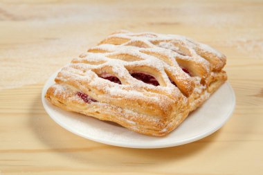 bir puf kek meyve doldurma ve çikolata beyaz tabakta ile pudra şekeri serpilir ve çikolata ile mavi bir arka plan üzerinde ahşap bir masaya döktü