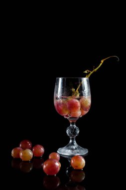 bir bardak üzüm çilek, şarap ve üzüm siyah bir zemin üzerine birkaç damla davul ile