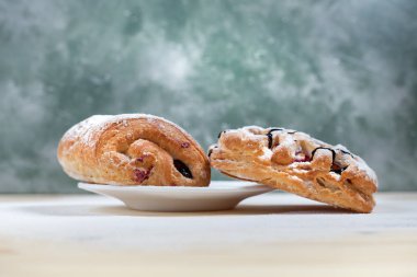 puf böreği berry doldurma ve çikolata ile ahşap arka plan üzerinde beyaz bir tepside pudra şekeri serpilir