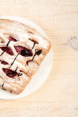 puf böreği berry doldurma ve çikolata ile ahşap arka plan üzerinde beyaz bir tepside pudra şekeri serpilir