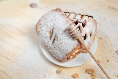 puf böreği berry doldurma ve çikolata ile ahşap arka plan üzerinde beyaz bir tepside pudra şekeri serpilir