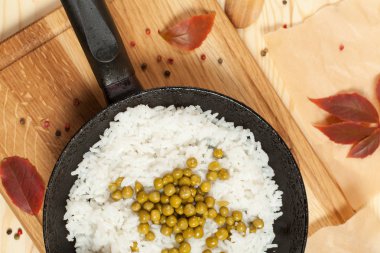 eski bir kızartma tavası sonbahar yaprakları ve biber ile çevrili bir ahşap zemin üzerine ahşap kesme tahtası üzerinde bezelye ile pirinç