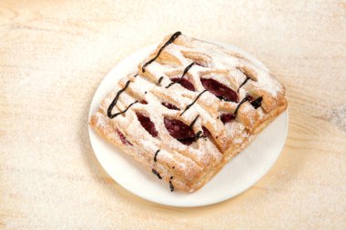 puf böreği berry doldurma ve çikolata ile ahşap arka plan üzerinde beyaz bir tepside pudra şekeri serpilir