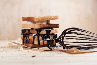 Kağıt ahşap arka plan üzerinde ahşap kesme tahtası üzerinde bir çırpma teli ile çikolata ile döktü bir muz ile tost