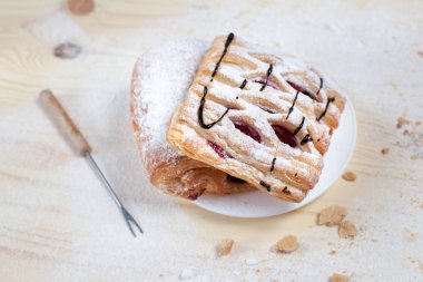 puf böreği berry doldurma ve çikolata ile ahşap arka plan üzerinde beyaz bir tepside pudra şekeri serpilir