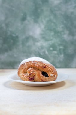 puf böreği berry doldurma ve çikolata ile ahşap arka plan üzerinde beyaz bir tepside pudra şekeri serpilir