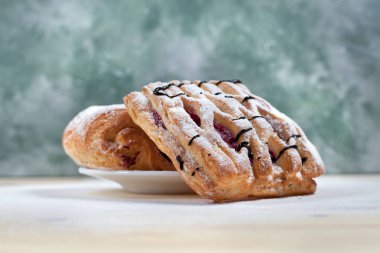 puf böreği berry doldurma ve çikolata ile ahşap arka plan üzerinde beyaz bir tepside pudra şekeri serpilir