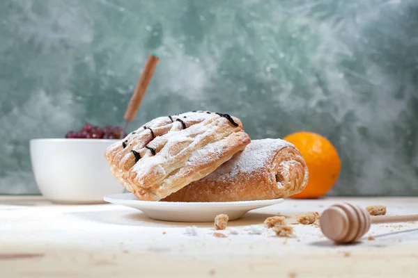 puf böreği berry doldurma ve çikolata, portakal ve üzüm ile ahşap arka plan üzerinde beyaz bir tepside pudra şekeri serpilir