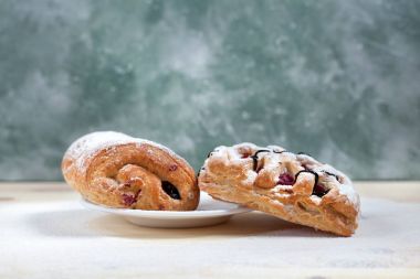 puf böreği berry doldurma ve çikolata ile ahşap arka plan üzerinde beyaz bir tepside pudra şekeri serpilir