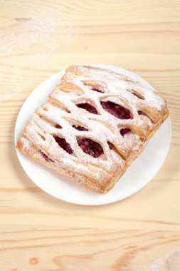 puf böreği berry doldurma ve çikolata ile ahşap arka plan üzerinde beyaz bir tepside pudra şekeri serpilir