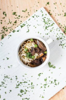 Makarna ve sebzeler ile Yeşiller ahşap arka plan üzerinde beyaz kesme tahtası üzerinde beyaz bir tabakta mantar çorbası