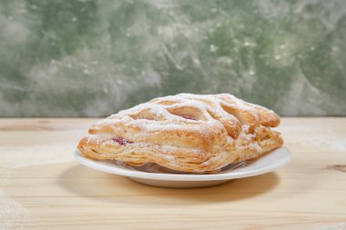 puf böreği berry doldurma ve çikolata ile ahşap arka plan üzerinde beyaz bir tepside pudra şekeri serpilir