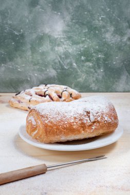 puf böreği berry doldurma ve çikolata ile ahşap arka plan üzerinde beyaz bir tepside pudra şekeri serpilir