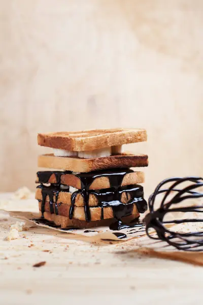木製の背景に木製まな板の上の紙にチョコレートを注ぎ、バナナとトーストします。 — ストック写真