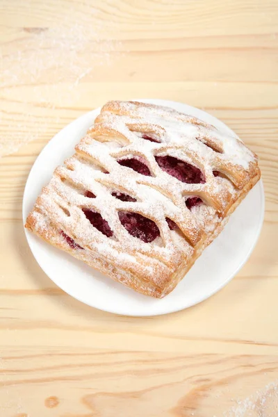 puf böreği berry doldurma ve çikolata ile ahşap arka plan üzerinde beyaz bir tepside pudra şekeri serpilir