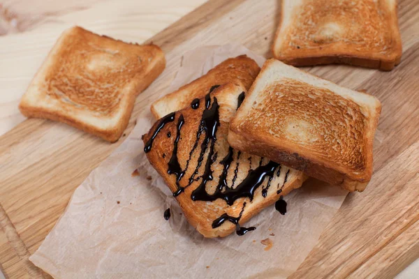 çikolata ile ahşap arka plan üzerinde bir ahşap kesme tahtası üzerinde kağıda döktü bir muz ile tost