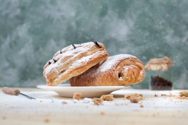 puf böreği berry doldurma ve çikolata ile ahşap arka plan üzerinde beyaz bir tepside pudra şekeri serpilir