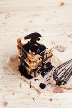 çikolata ile bir çırpma teli ile ahşap arka plan üzerinde bir ahşap kesme tahtası üzerinde kağıda döktü bir muz ile tost