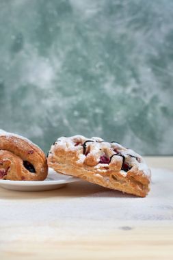 puf böreği berry doldurma ve çikolata ile ahşap arka plan üzerinde beyaz bir tepside pudra şekeri serpilir