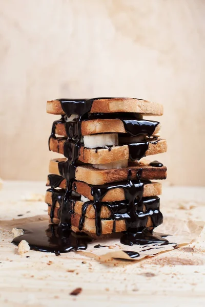 çikolata ile ahşap arka plan üzerinde bir ahşap kesme tahtası üzerinde kağıda döktü bir muz ile tost