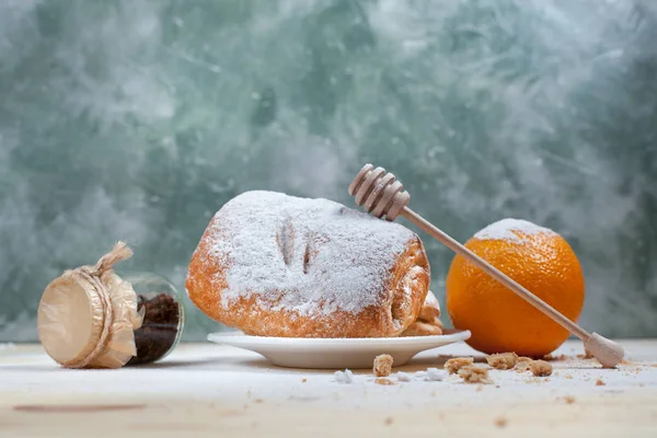 puf böreği berry doldurma ve çikolata, portakal ve üzüm ile ahşap arka plan üzerinde beyaz bir tepside pudra şekeri serpilir