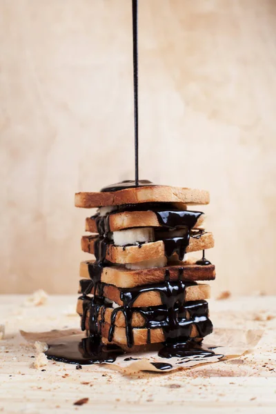 çikolata ile ahşap arka plan üzerinde bir ahşap kesme tahtası üzerinde kağıda döktü bir muz ile tost