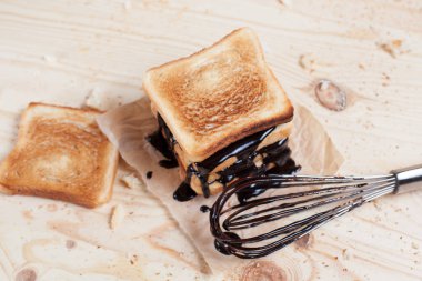 çikolata ile bir çırpma teli ile ahşap arka plan üzerinde bir ahşap kesme tahtası üzerinde kağıda döktü bir muz ile tost