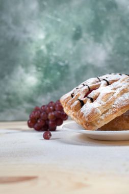 puf böreği berry doldurma ve çikolata ile ahşap arka plan üzerinde beyaz bir tepside pudra şekeri serpilir