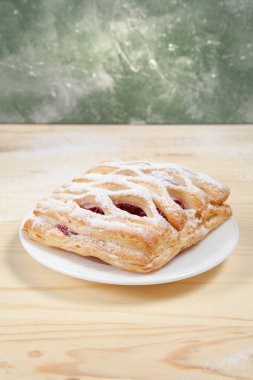 puf böreği berry doldurma ve çikolata ile ahşap arka plan üzerinde beyaz bir tepside pudra şekeri serpilir