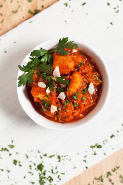 etli sebze ışık ahşap arka plan üzerinde beyaz kesme tahtası üzerinde beyaz bir kapta sarımsak sosu altında otlar ile serpilir