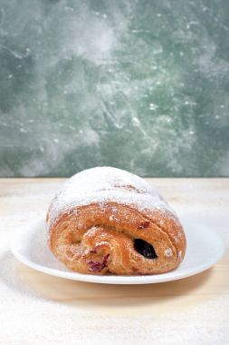 puf böreği berry doldurma ve çikolata ile ahşap arka plan üzerinde beyaz bir tepside pudra şekeri serpilir