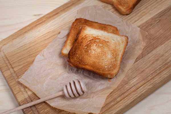 Pane tostato con una banana, versato con cioccolato su carta su un tagliere di legno, su uno sfondo di legno — Foto Stock
