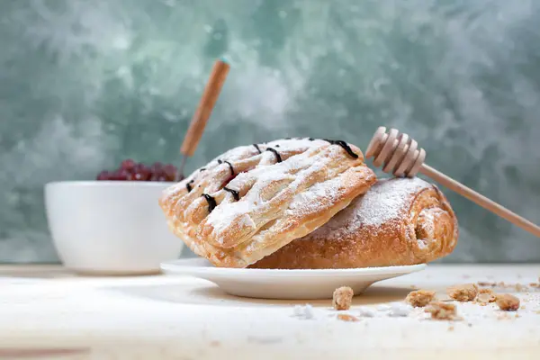 puf böreği berry doldurma ve çikolata ile ahşap arka plan üzerinde beyaz bir tepside pudra şekeri serpilir