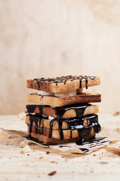 çikolata ile ahşap arka plan üzerinde bir ahşap kesme tahtası üzerinde kağıda döktü bir muz ile tost