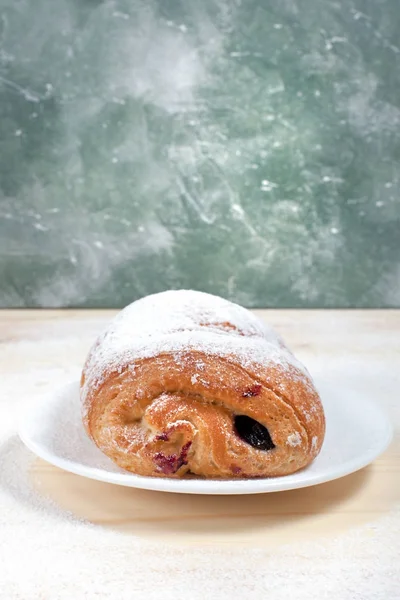 puf böreği berry doldurma ve çikolata ile ahşap arka plan üzerinde beyaz bir tepside pudra şekeri serpilir