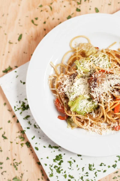 hafif ahşap arka plan üzerinde beyaz kesme tahtası üzerinde beyaz bir tabakta sebze ve et ile makarna otlar ile serpilir