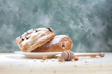 puf böreği berry doldurma ve çikolata ile ahşap arka plan üzerinde beyaz bir tepside pudra şekeri serpilir