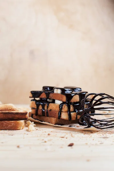 Çikolata ile bir çırpma teli ile ahşap arka plan üzerinde bir ahşap kesme tahtası üzerinde kağıda döktü bir muz ile tost — Stok fotoğraf