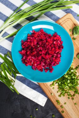 pancar, ahşap kesme tahtası üzerinde yeşil soğan, koyu ahşap arka plan üzerinde çizgili mutfak havlusu ile salata