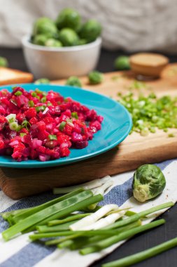 salata pancar, sarımsak, yeşil soğan ve Brüksel lahanası ahşap kesme tahtası üzerinde bir kase ile mutfak havlusu koyu ahşap zemin çizgili