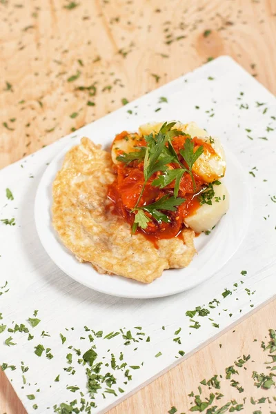 hamuru patates ve beyaz kesme tahtası hafif ahşap arka plan üzerinde beyaz bir tabağa sosu ile Chop pirzola otlar ile serpilir