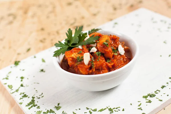 etli sebze ışık ahşap arka plan üzerinde beyaz kesme tahtası üzerinde beyaz bir kapta sarımsak sosu altında otlar ile serpilir