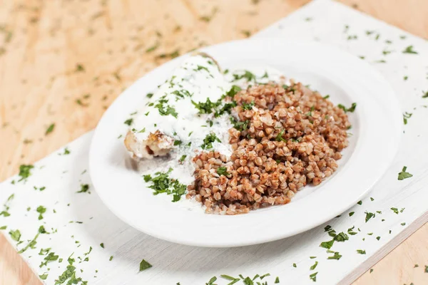 karabuğday balık sosu hafif ahşap arka plan üzerinde beyaz kesme tahtası üzerinde beyaz bir tabakta altında otlar ile serpilir