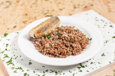 buğday ile ışık ahşap arka plan üzerinde beyaz kesme tahtası üzerinde beyaz bir plaka üzerinde balık otlar ile serpilir