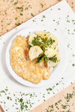 bir meyilli ahşap arka plan otlar ile serpilir ateşin üzerinde beyaz kesme tahtası üzerinde beyaz bir tabakta patates ile doğrayın