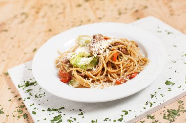 hafif ahşap arka plan üzerinde beyaz kesme tahtası üzerinde beyaz bir tabakta sebze ve et ile makarna otlar ile serpilir