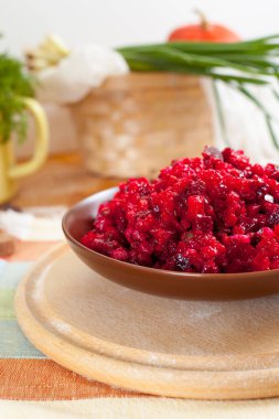Geleneksel Rus pancar salatası salata yeşilliklerle çevrili bir çizgili havlu üzerinde ahşap kesme tahtası üzerinde bir kahverengi kil kase